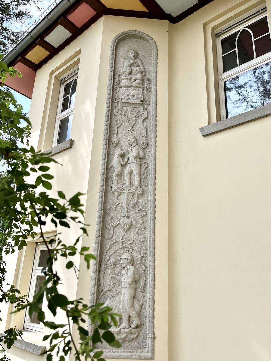Steinrelief an der Fassade mit Szenen aus Märchen und biblischen Geschichten